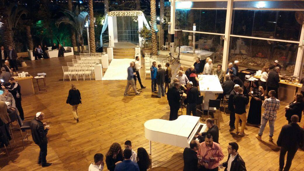 פסנתר כנף לבן בקבלת הפנים של אירוע מפואר עם אורחים סביב